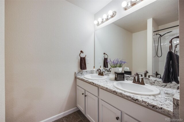 bathroom with double vanity, tile patterned flooring, a shower, and baseboards