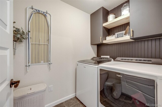 laundry area featuring cabinet space, washer and dryer, baseboards, and dark tile patterned floors