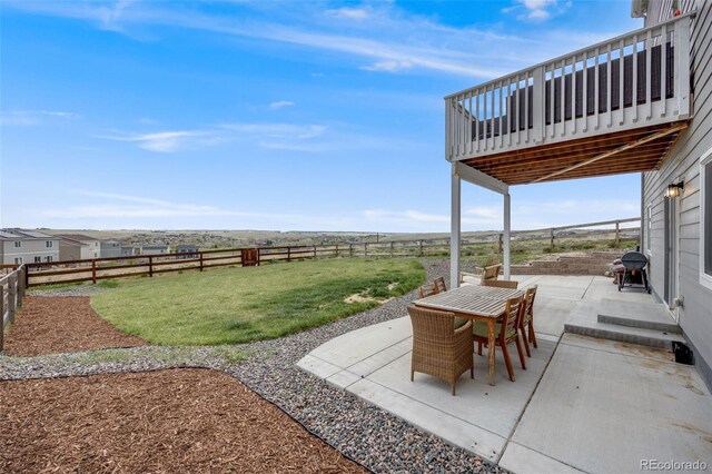 view of yard with a patio area, outdoor dining space, a deck, and a view of countryside