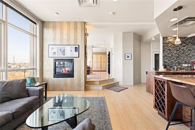 living area with a large fireplace, visible vents, and light wood-style flooring