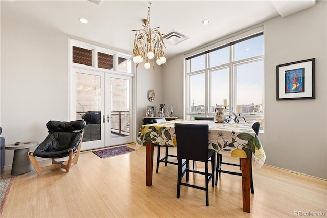 dining space featuring visible vents, french doors, light wood-type flooring, floor to ceiling windows, and an inviting chandelier