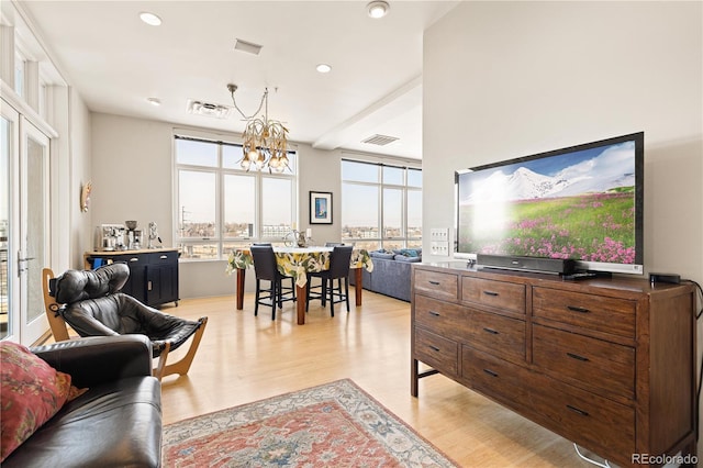 living room with light wood finished floors, visible vents, and an inviting chandelier