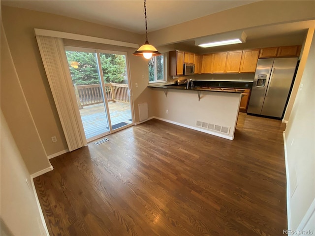 kitchen with dark countertops, a peninsula, visible vents, and stainless steel appliances