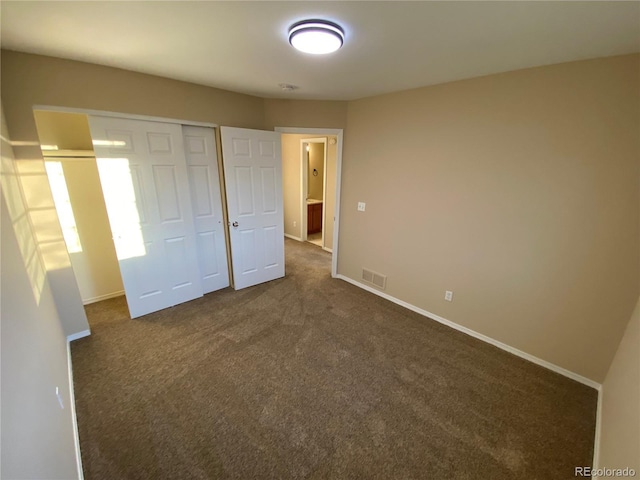 unfurnished bedroom featuring a closet, visible vents, baseboards, and dark colored carpet