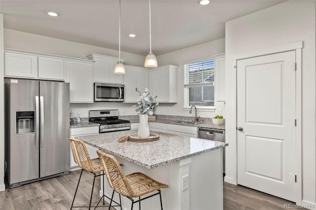 kitchen with white cabinets, appliances with stainless steel finishes, a kitchen island, and sink