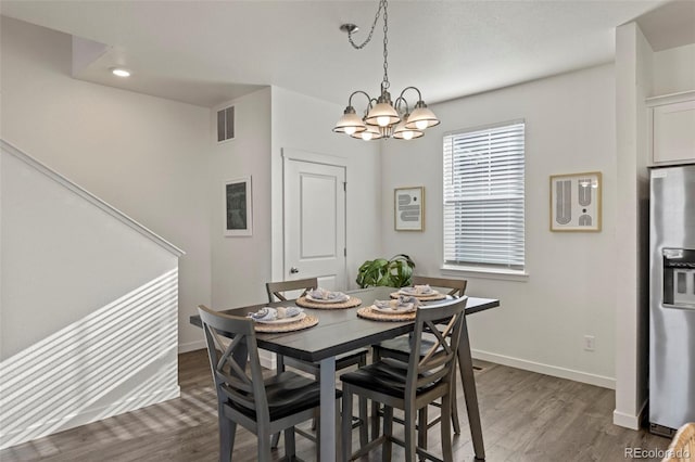 dining space featuring dark wood-type flooring and a chandelier