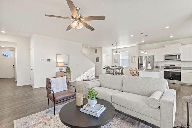 living room with dark wood-type flooring and ceiling fan with notable chandelier