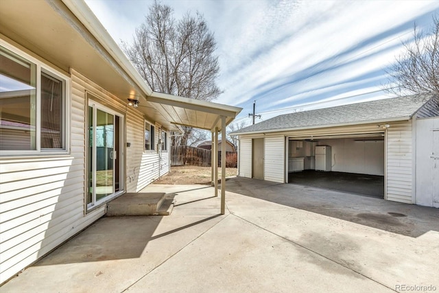 view of patio featuring a garage, an outdoor structure, and fence