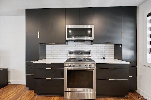 9563 W Caley Ave, Littleton, CO 80123 - kitchen featuring appliances with stainless steel finishes, light countertops, tasteful backsplash, and dark wood-style floors