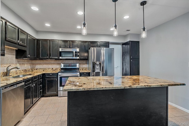 kitchen with appliances with stainless steel finishes, backsplash, sink, decorative light fixtures, and a center island