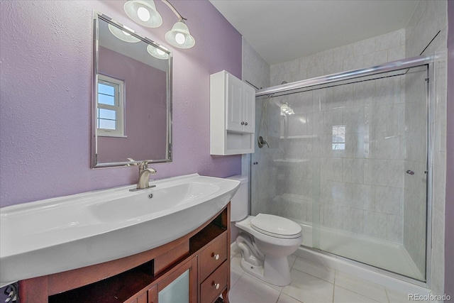 bathroom featuring tile patterned floors, vanity, toilet, and a shower with door