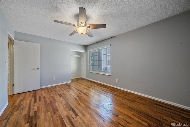 unfurnished bedroom featuring a textured ceiling, hardwood / wood-style flooring, a closet, and ceiling fan