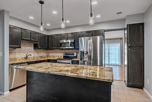 kitchen with decorative backsplash, a center island, hanging light fixtures, and appliances with stainless steel finishes