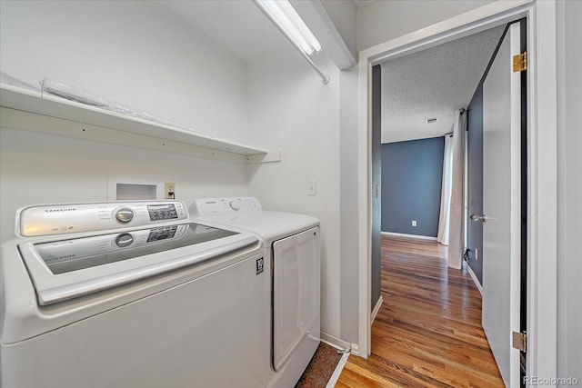 laundry area with washer and clothes dryer, a textured ceiling, and hardwood / wood-style floors