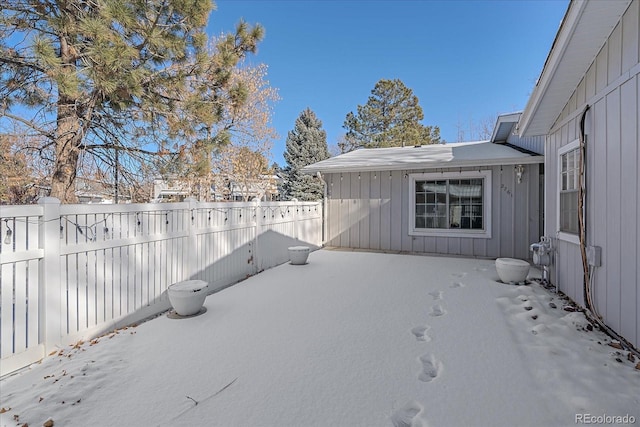 snowy yard featuring a fenced backyard and a patio area