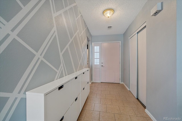 doorway to outside with visible vents, a textured ceiling, and light tile patterned flooring