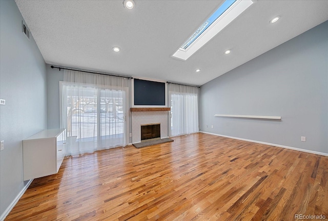 unfurnished living room featuring a wealth of natural light, recessed lighting, a fireplace with raised hearth, and light wood-style flooring
