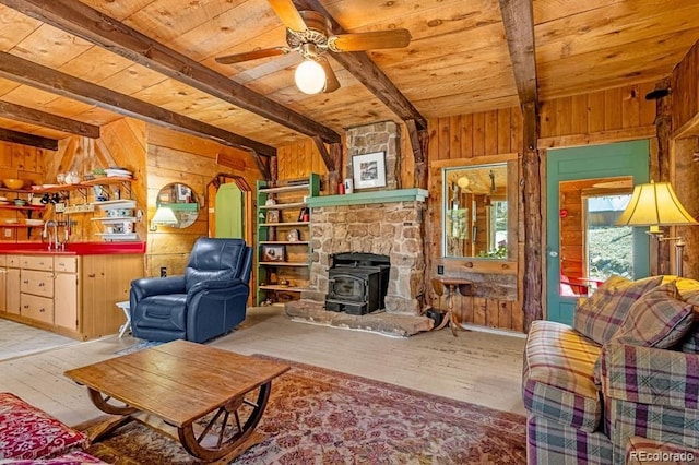 8929 Apache Dr, Beulah, CO 81023 - living area with a wooden ceiling with exposed beams, wood walls, hardwood / wood-style floors, a wood stove, and ceiling fan