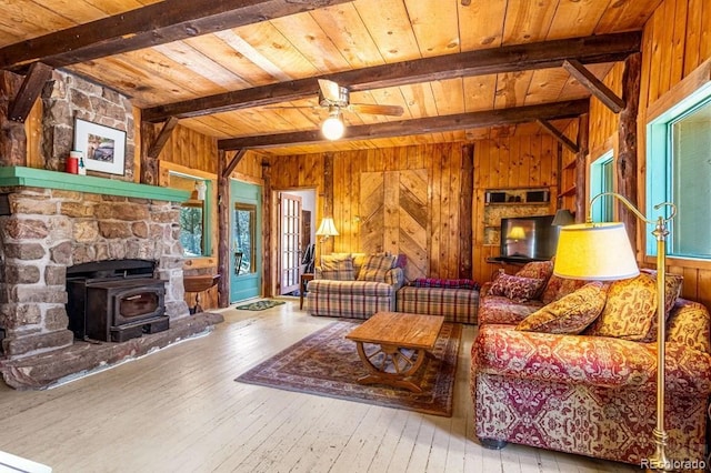 8929 Apache Dr, Beulah, CO 81023 - living area featuring wood walls, a wooden ceiling with exposed beams, wood-type flooring, a wood stove, and a ceiling fan