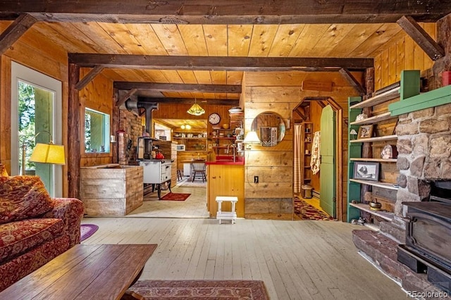 8929 Apache Dr, Beulah, CO 81023 - living room featuring wooden walls, a wood stove, hardwood / wood-style flooring, a wood ceiling with exposed beams, and arched walkways