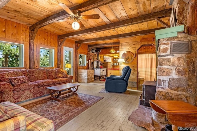 8929 Apache Dr, Beulah, CO 81023 - living room with wood walls, a wooden ceiling with exposed beams, hardwood / wood-style flooring, ceiling fan, and a wood stove