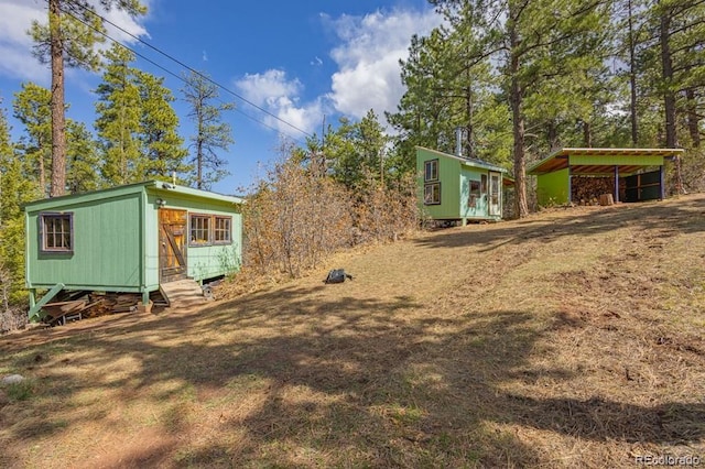 8929 Apache Dr, Beulah, CO 81023 - view of yard featuring a detached carport, an outbuilding, and entry steps