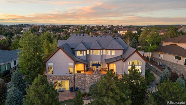 5171 Shade Tree Ln, Parker, CO 80134 - back of house at dusk with stucco siding, stone siding, and a residential view