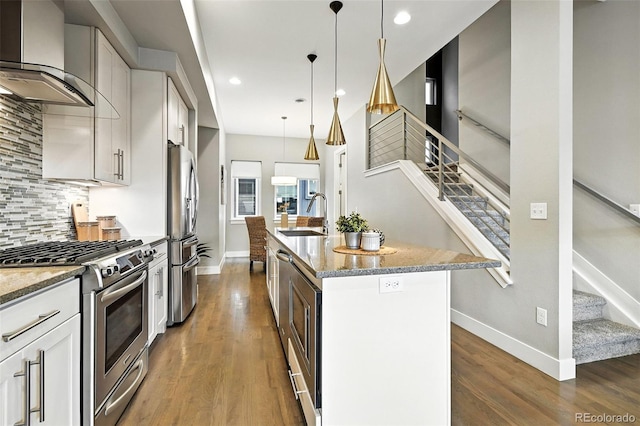 3431 W 16th Ave, Denver, CO 80204 - kitchen featuring stainless steel appliances, wall chimney exhaust hood, light stone countertops, backsplash, and wood finished floors