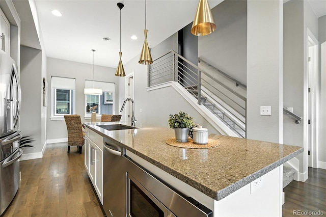 3431 W 16th Ave, Denver, CO 80204 - kitchen with stainless steel appliances, a kitchen island with sink, white cabinets, dark wood-type flooring, and light stone countertops