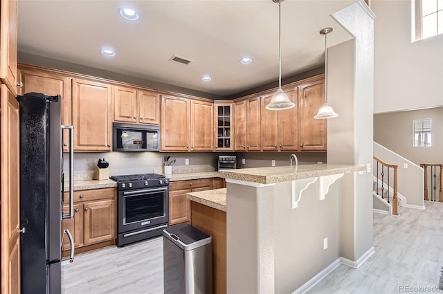 kitchen with visible vents, freestanding refrigerator, a peninsula, black range with gas stovetop, and built in microwave