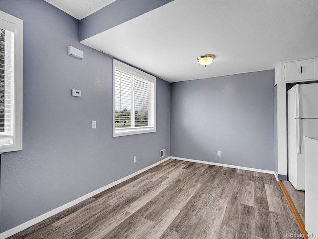 empty room featuring baseboards, visible vents, and wood finished floors