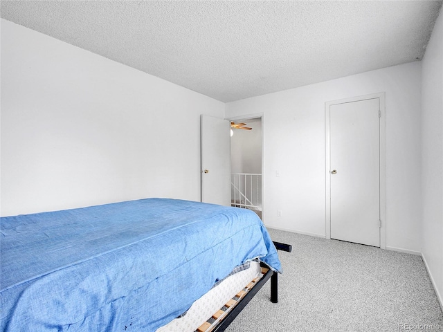 bedroom with a textured ceiling, baseboards, and carpet floors