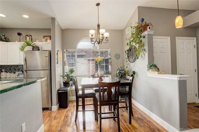 dining area featuring baseboards, light wood finished floors, and a chandelier