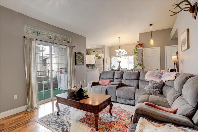 living area featuring light wood-style floors, baseboards, and a notable chandelier