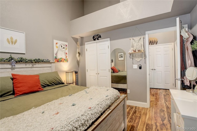 bedroom with a closet, light wood-style floors, baseboards, and arched walkways