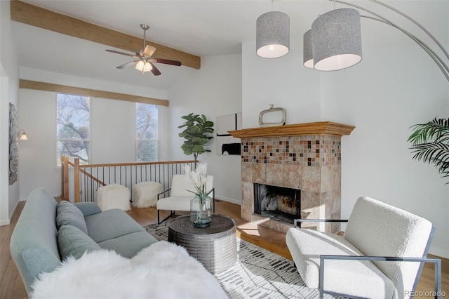 living room with beam ceiling, wood finished floors, baseboards, and a tile fireplace