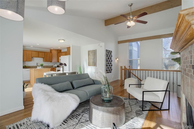 living room featuring lofted ceiling with beams, light wood-style floors, and baseboards