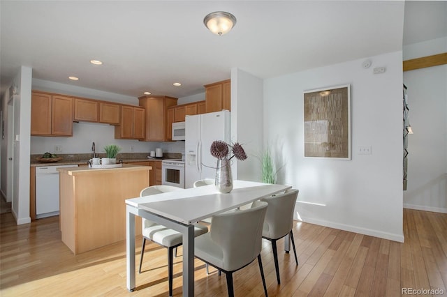 kitchen with recessed lighting, white appliances, a kitchen island, and light wood finished floors