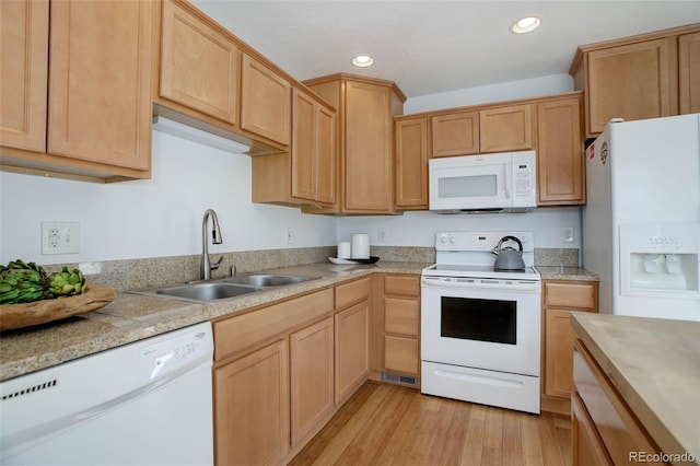 kitchen with white appliances, light countertops, light wood-style floors, and a sink