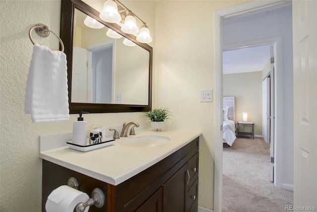 ensuite bathroom featuring connected bathroom, baseboards, vanity, and a textured wall