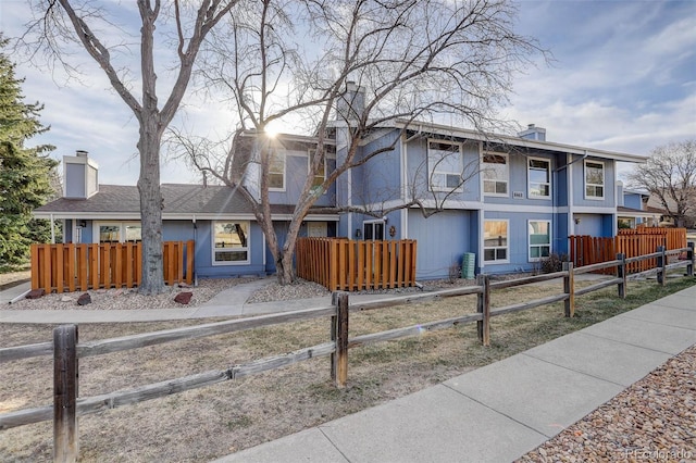 view of front of house featuring a fenced front yard, stucco siding, and a chimney