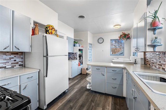 kitchen with dark hardwood / wood-style floors, white refrigerator, gray cabinets, decorative backsplash, and range