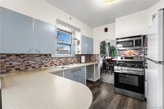 kitchen with sink, tasteful backsplash, dark hardwood / wood-style flooring, blue cabinets, and appliances with stainless steel finishes