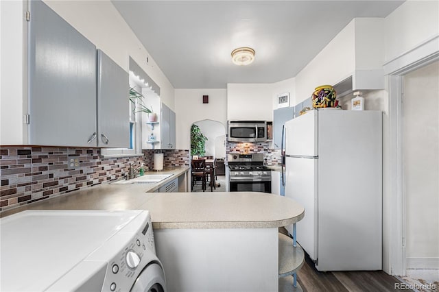 kitchen with kitchen peninsula, stainless steel appliances, washer / clothes dryer, and sink