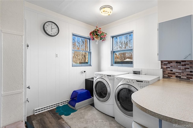 clothes washing area featuring light hardwood / wood-style floors, washer and clothes dryer, and wooden walls