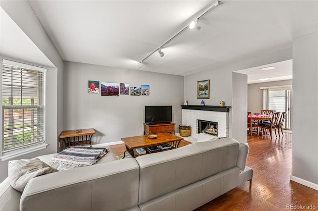 living room featuring hardwood / wood-style floors, a fireplace, and rail lighting