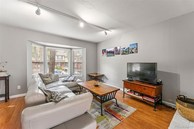 living room with wood-type flooring, track lighting, and a textured ceiling