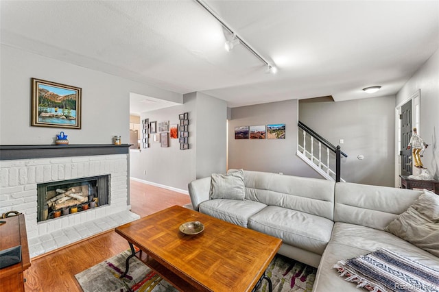 living room featuring wood-type flooring, a fireplace, and rail lighting