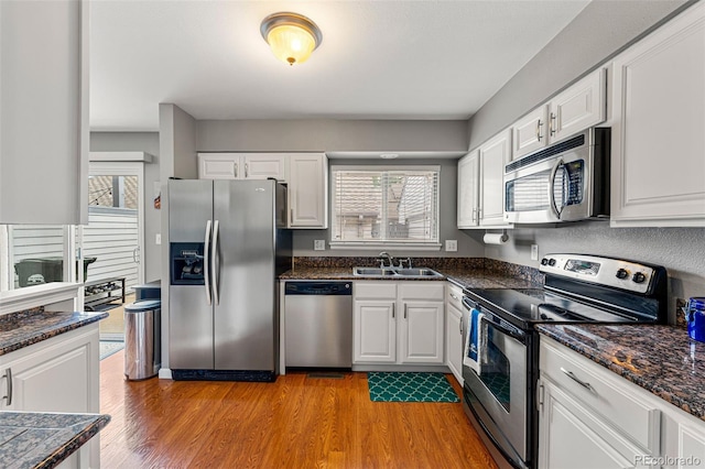 kitchen featuring appliances with stainless steel finishes, sink, white cabinetry, and light hardwood / wood-style flooring