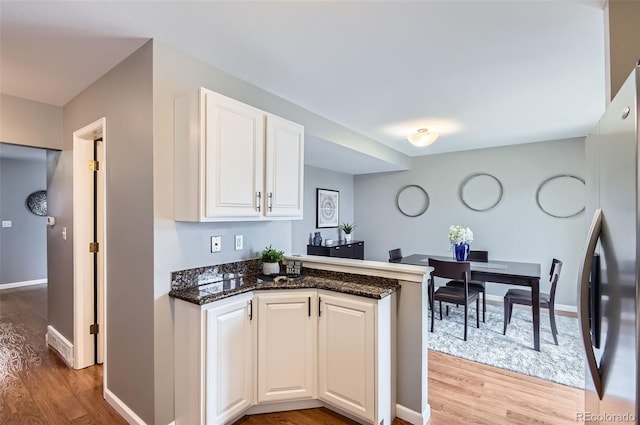 kitchen featuring baseboards, freestanding refrigerator, a peninsula, and light wood-style flooring